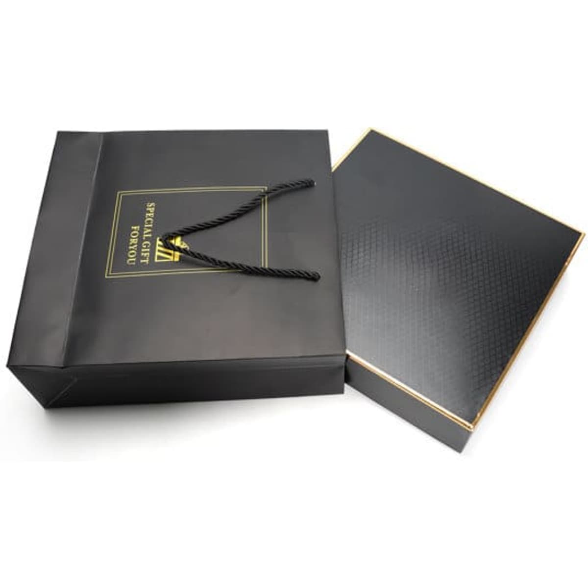 A black gift box set with a gold-trimmed lid, accompanied by a black shopping bag featuring a logo.