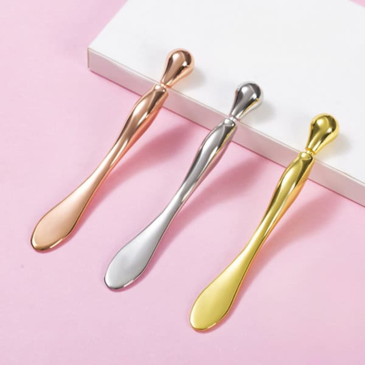 A set of three eye roller massage sticks in rose gold, silver, and gold, displayed on a light background.