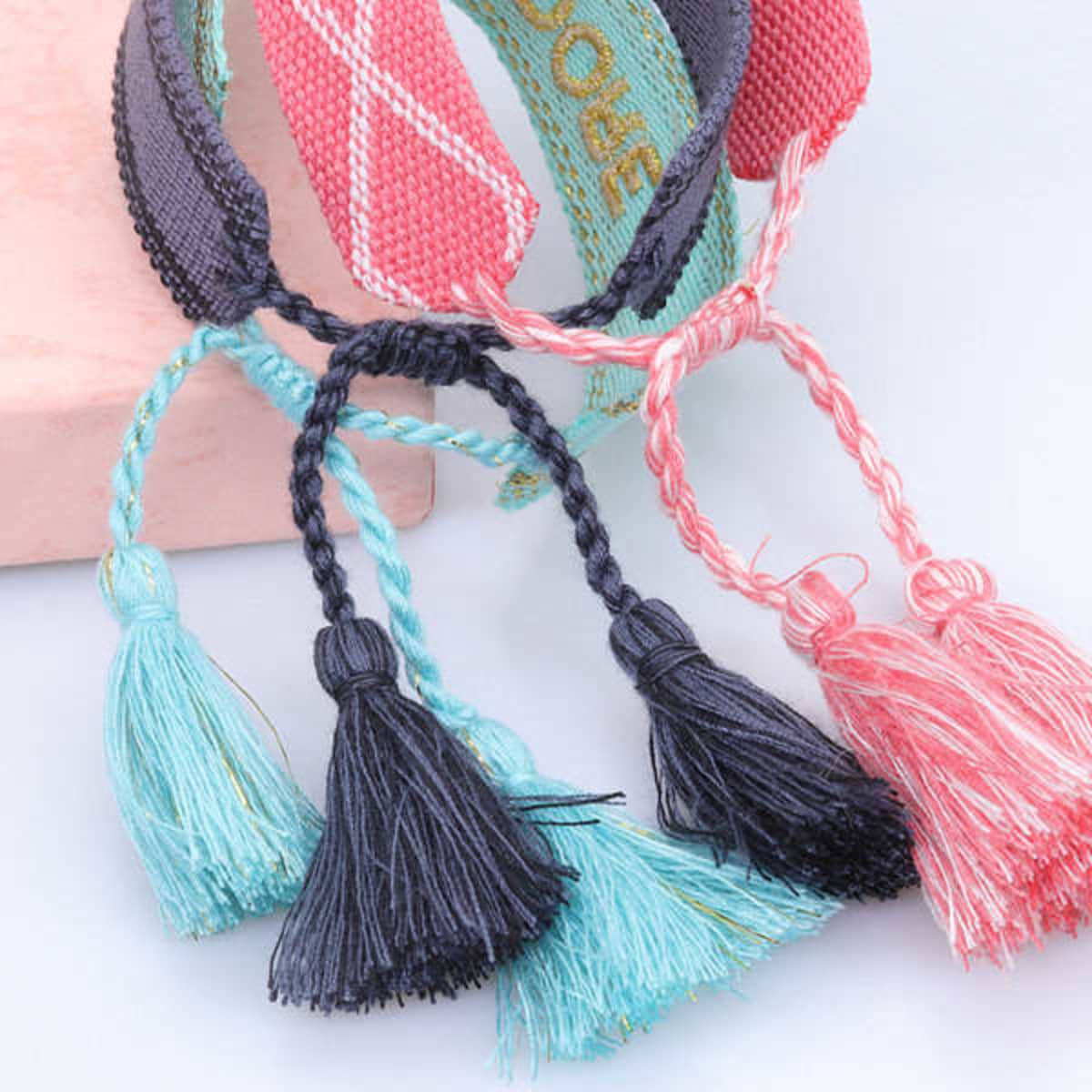 A collection of adjustable women's bracelets featuring colourful embroidery and decorative tassels in blue, black, and pink.