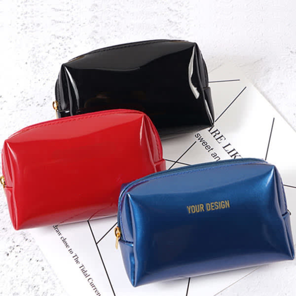 A set of three portable travel makeup bags in black, red, and blue, featuring a branding logo on the blue bag.