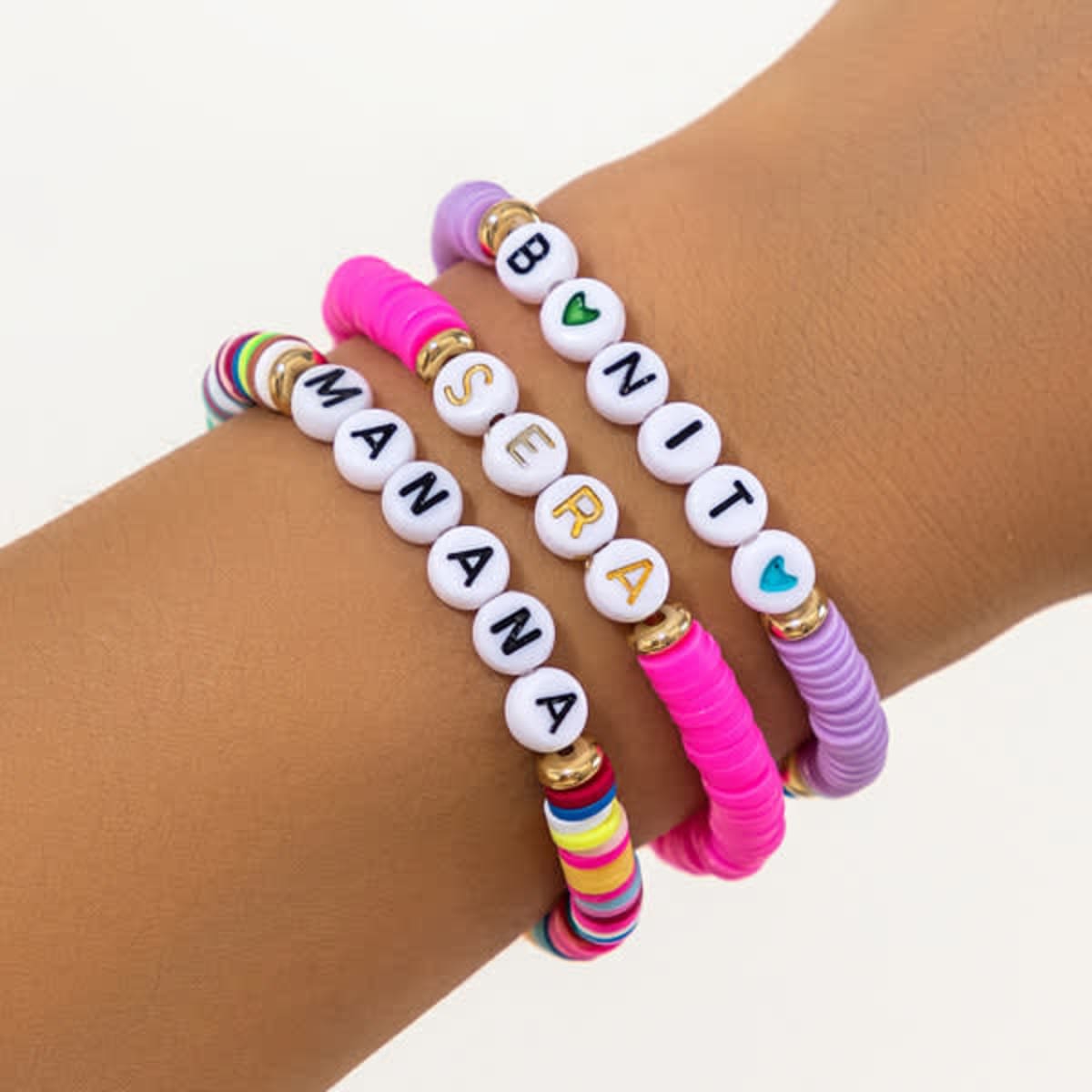 A stackable bracelet set featuring colourful beads in pink, purple, and multi-coloured designs with lettered beads.