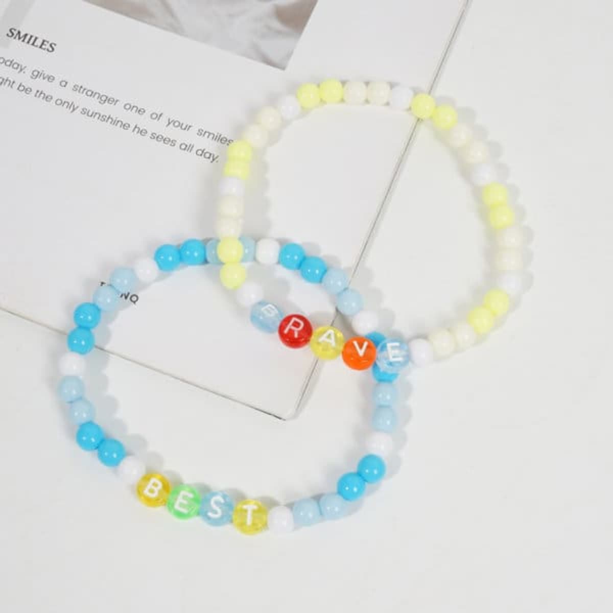 Two clay bead friendship bracelets in yellow, blue, and white, featuring the words "BEST" and "RAVE."