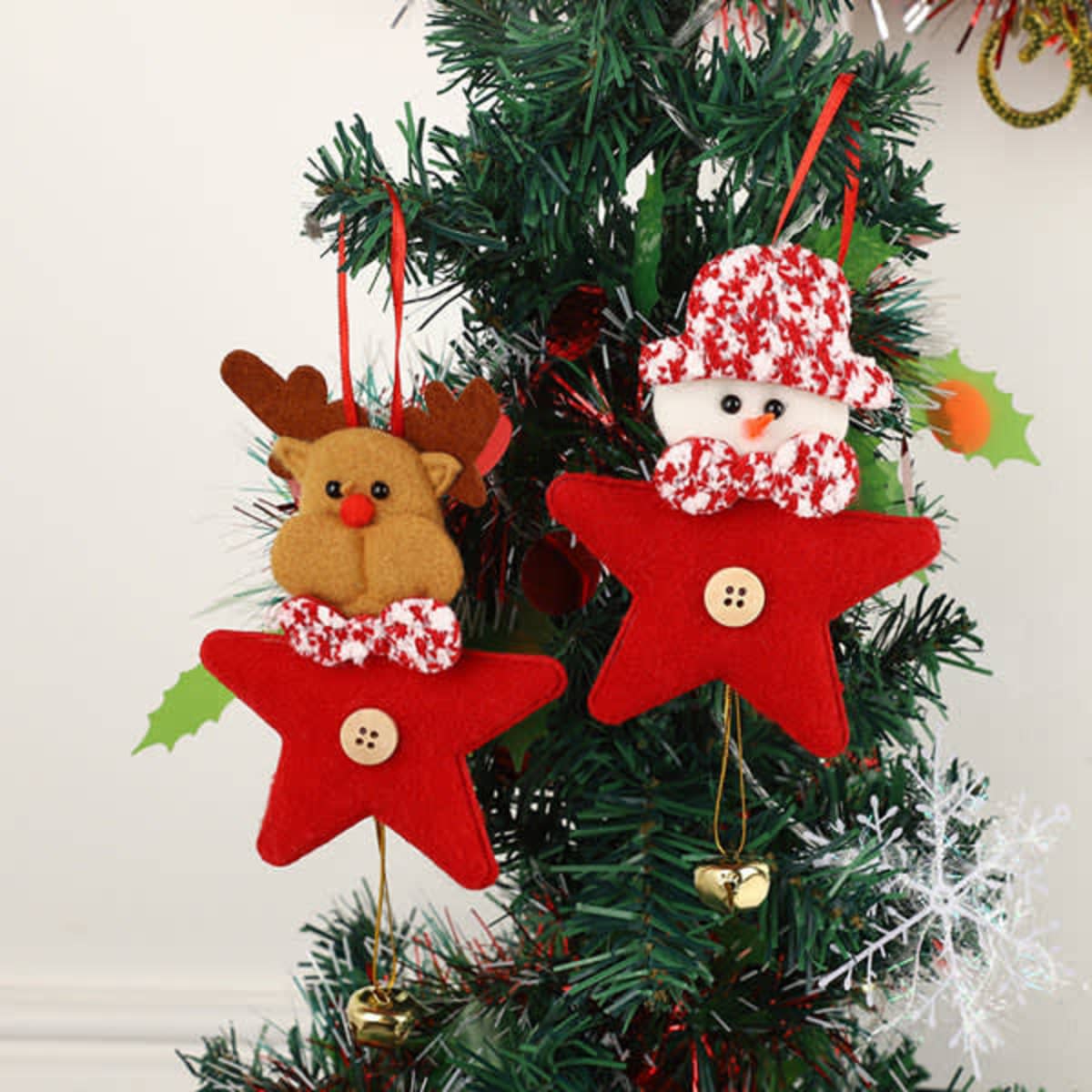 Two red star-shaped ornaments featuring a reindeer and a snowman, each with decorative buttons, hanging on a festive tree.