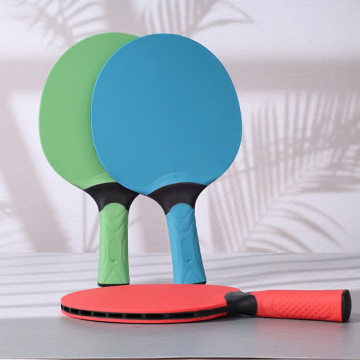 Custom table tennis rackets in blue, green, and red, featuring textured black grips and a sleek design.