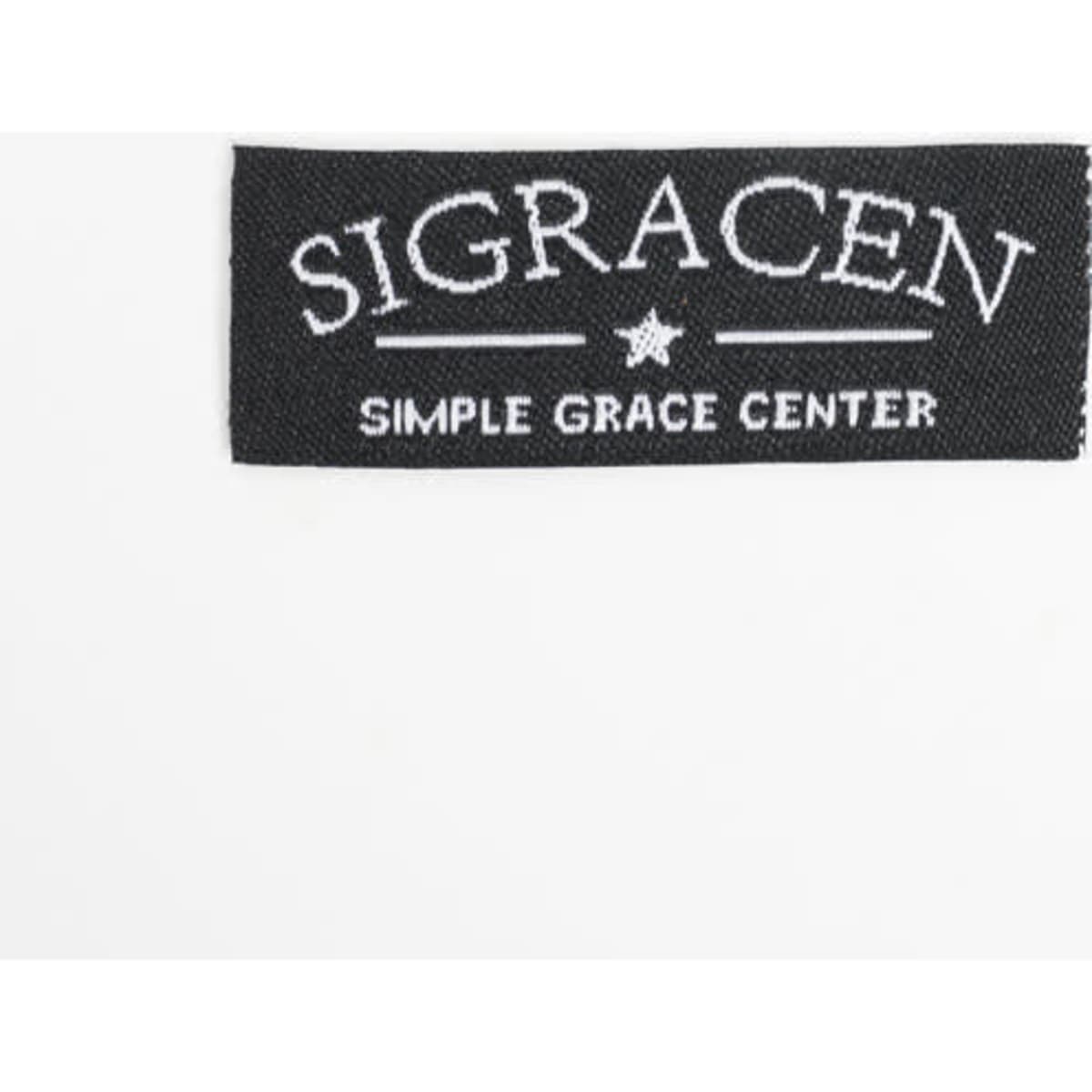 A black woven sewing label featuring white embroidered text and a star design.