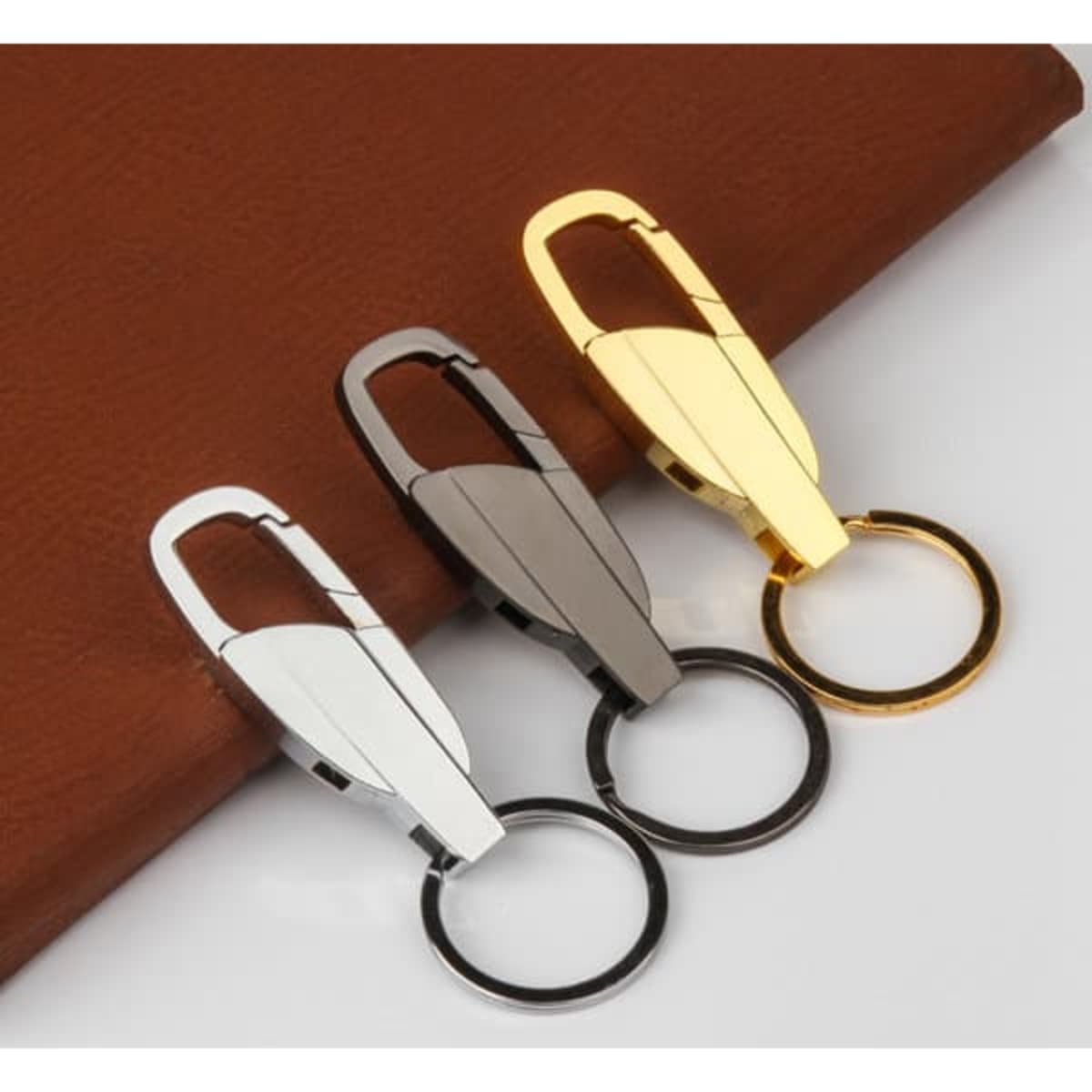 A zinc alloy car keychain in silver, grey, and gold finishes, featuring a keyring and sleek design.