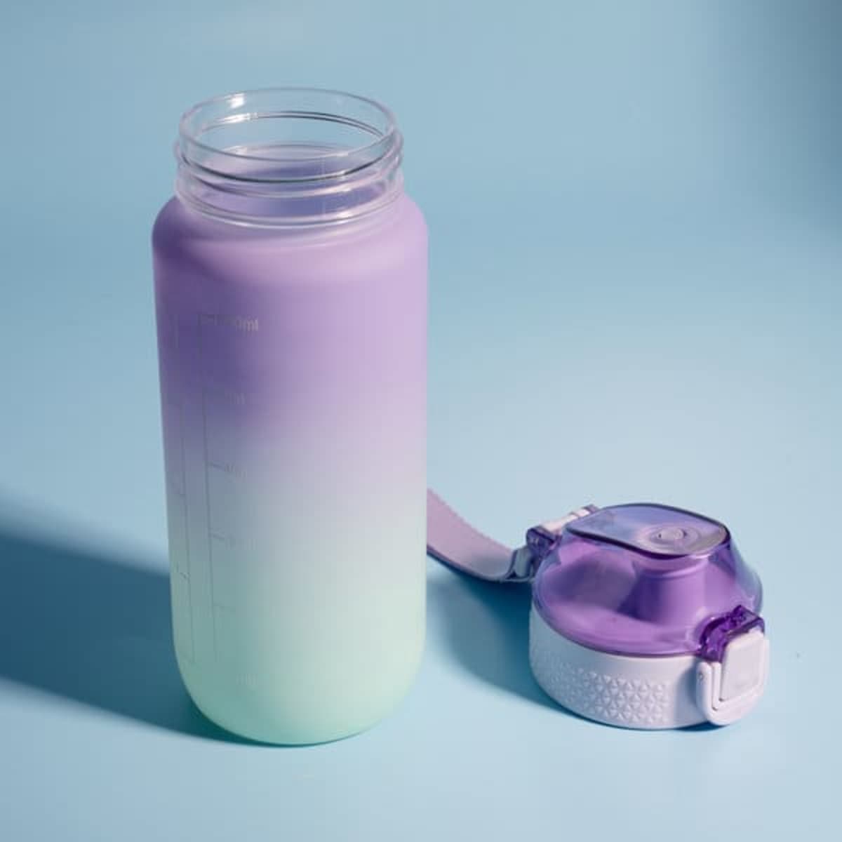 A drink bottle in a gradient of purple to mint green, featuring a removable lid and a logo.