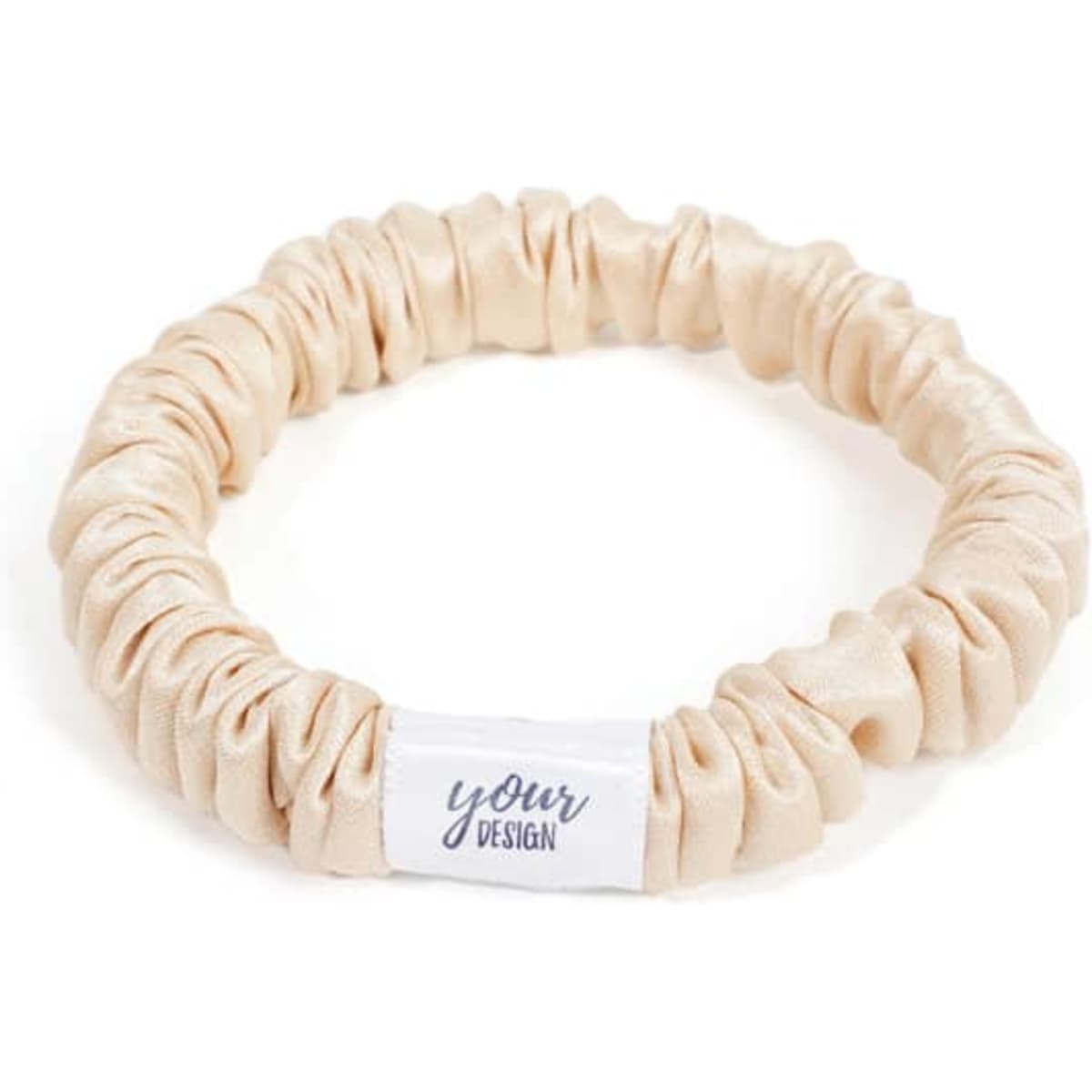 A silk hair scrunchie in a light beige colour with a white label featuring a logo.