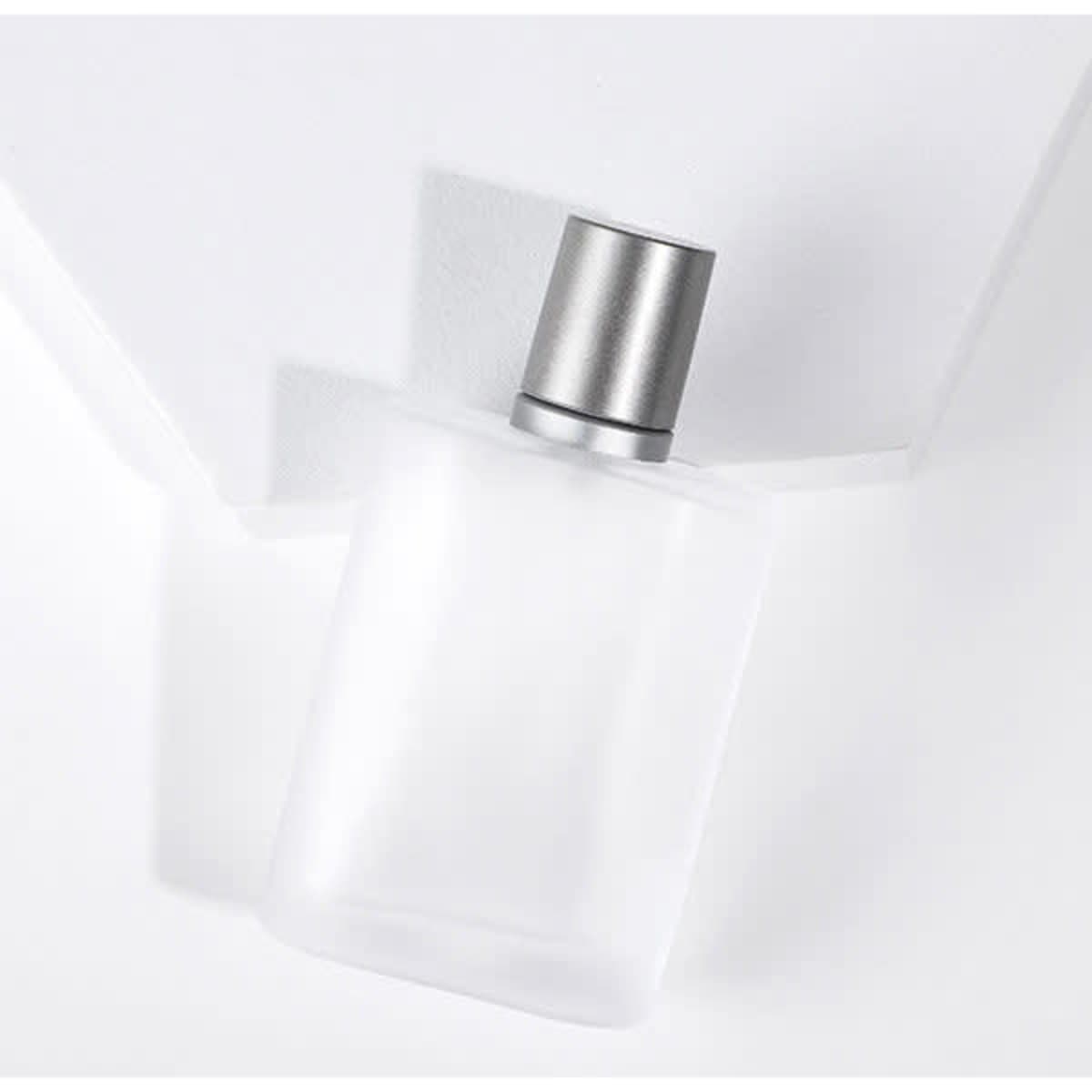 A thick glass travel perfume spray bottle with a silver cap, featuring a smooth, frosted finish.