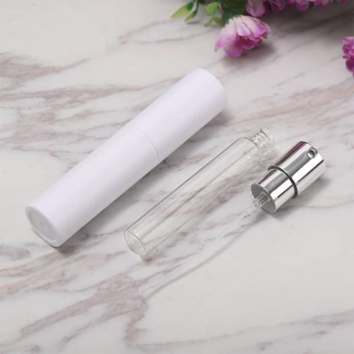 A portable twist spray perfume bottle, featuring a clear glass vial and a white cap with a silver spray nozzle.