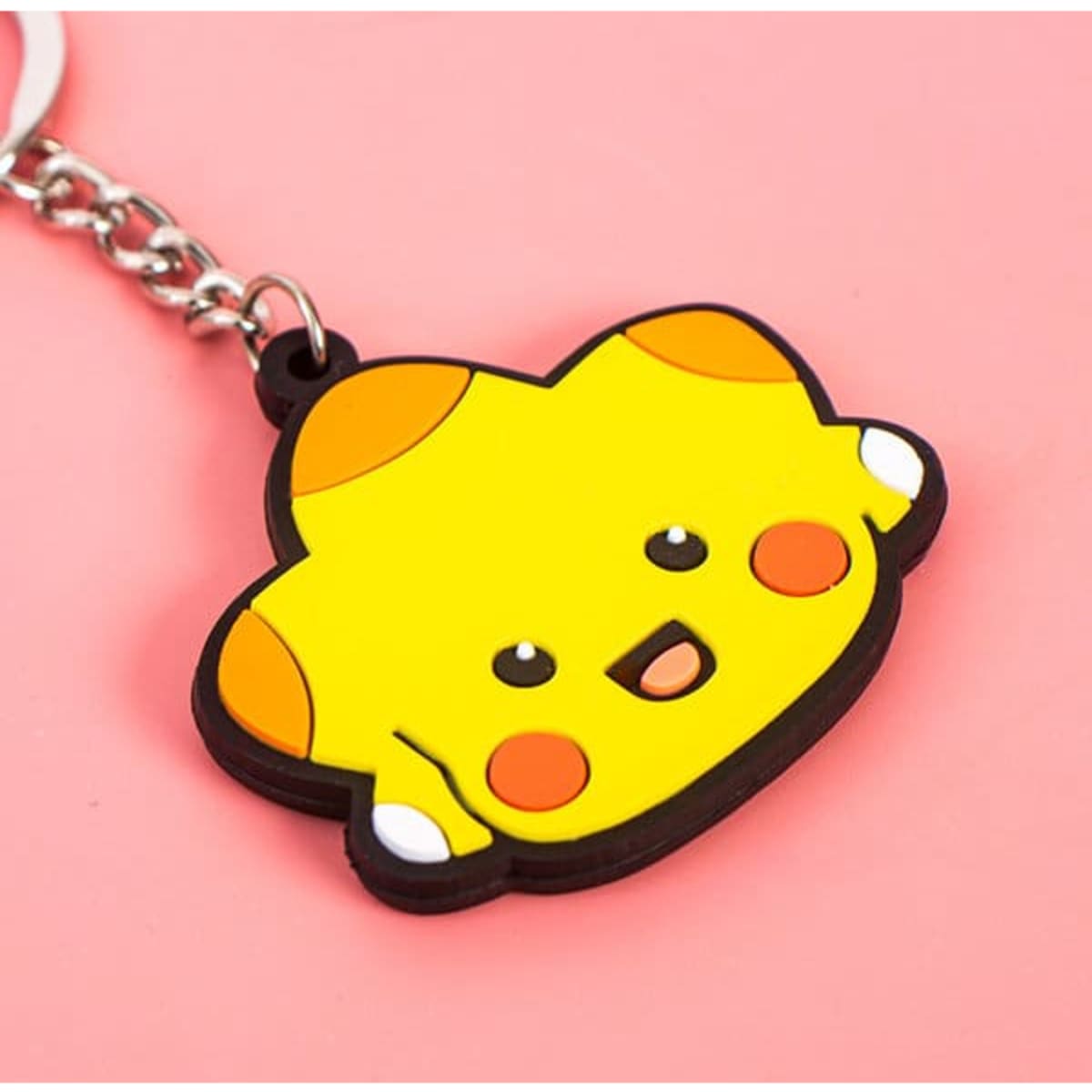 A yellow rubber keyring featuring a cute character with a smiling face and orange accents, attached to a metal chain.