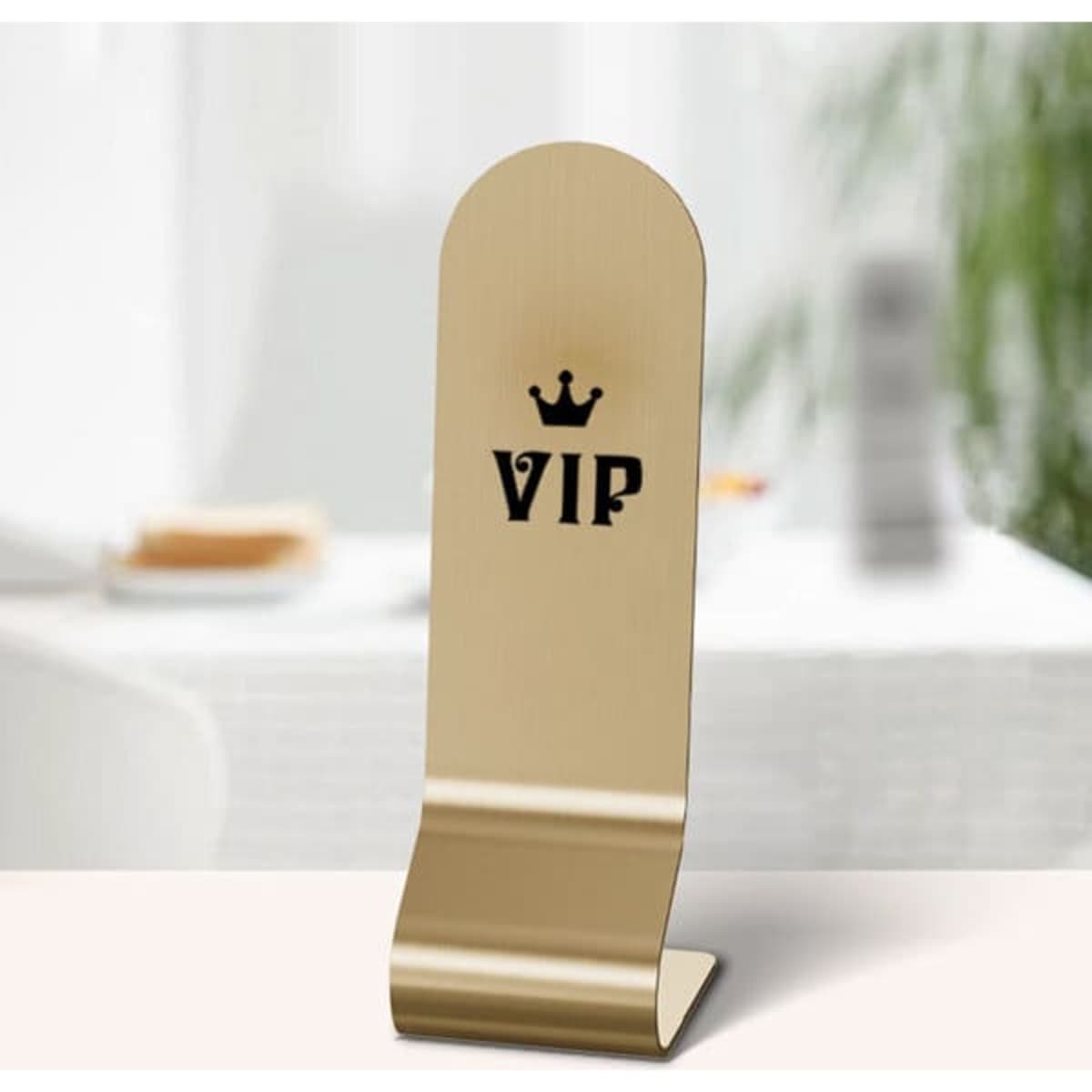 A gold stainless steel table tent sign with a logo, featuring a curved top and a sturdy base.