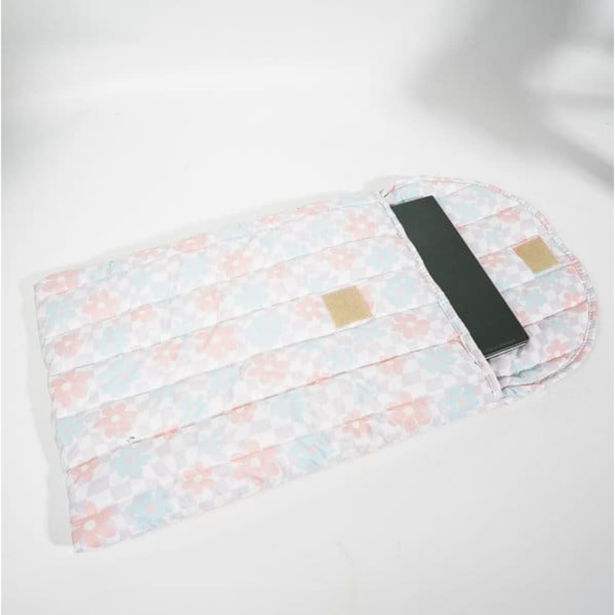 A puffy quilted tablet sleeve bag in pastel pink and blue floral design, featuring a dark green interior and a logo.