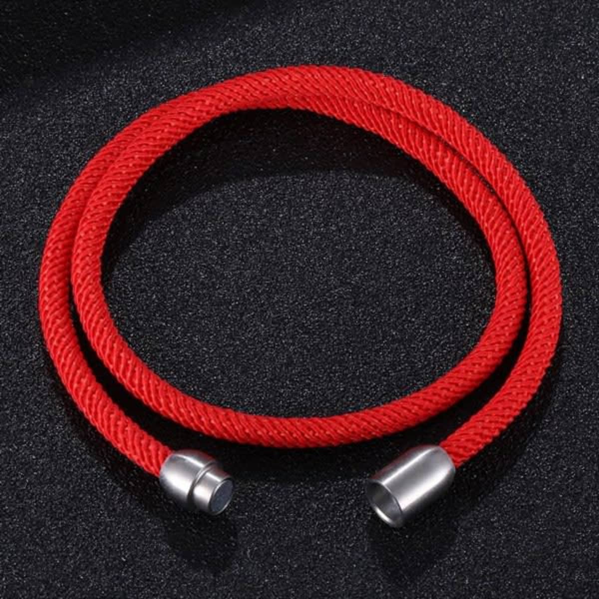 A red double-layer rope bracelet with a magnetic clasp and silver ends, resting on a black surface.