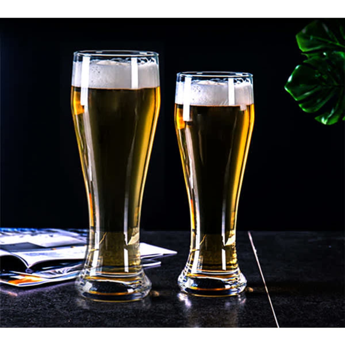 Two clear glass pilsner beer glasses are filled with golden beer and topped with frothy white foam.