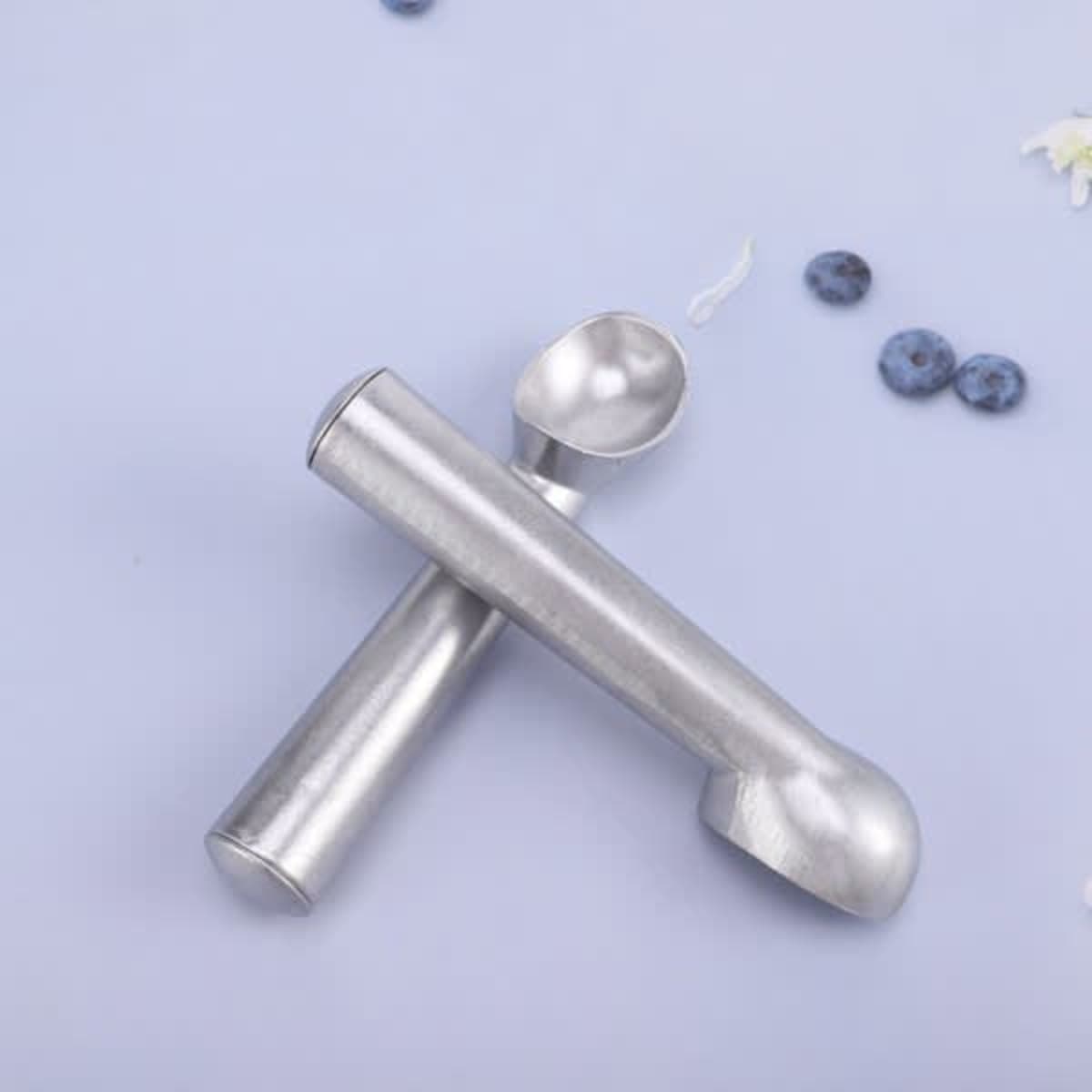 A nonstick aluminium ice cream scoop in a silver finish, placed on a light blue surface with scattered blueberries.