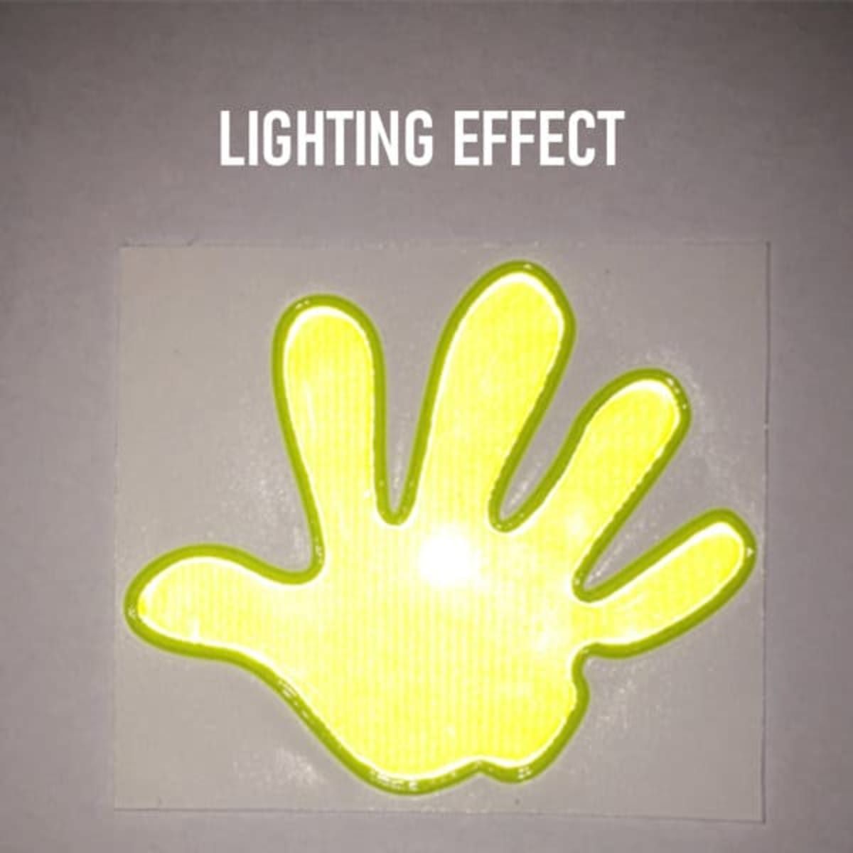 A reflective hand-shaped sticker in bright yellow with a glowing effect against a light background.