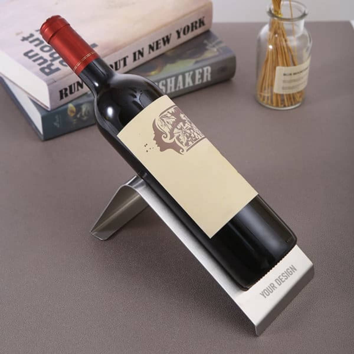 A drink bottle holder in stainless steel, angled to display a red wine bottle with a blank label, against a stylish background.
