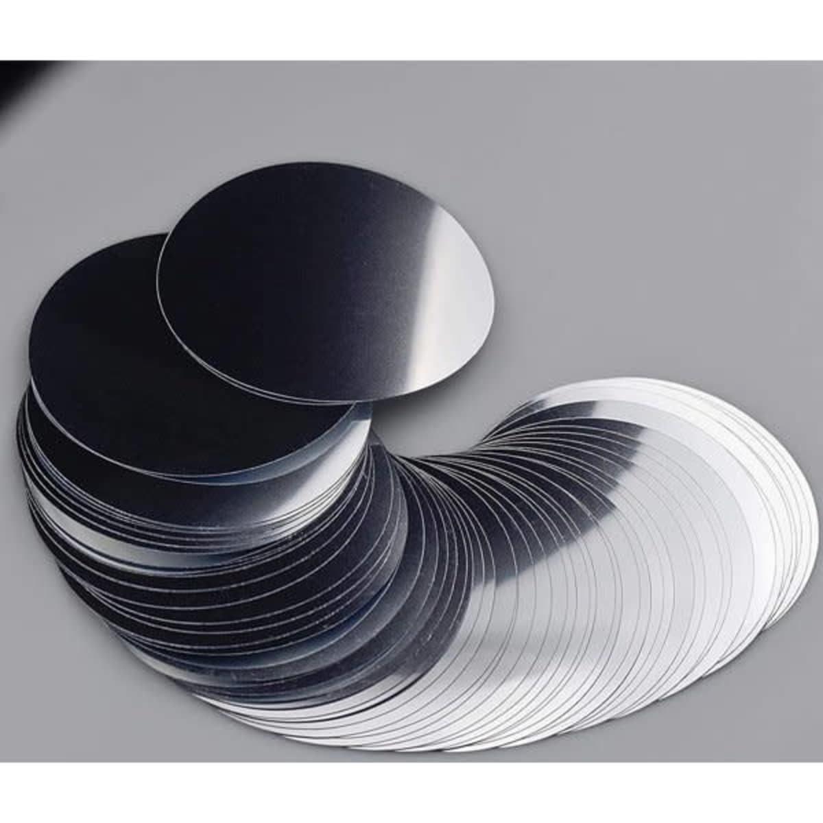 A collection of silver wine pourer discs arranged in a flowing pattern on a grey background, featuring a shiny finish.