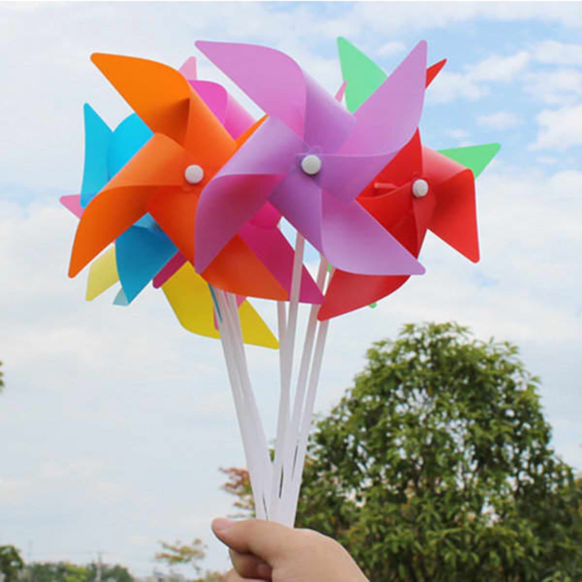 A colourful assortment of hand-held windmills featuring pink, blue, orange, green, and yellow blades on white sticks.