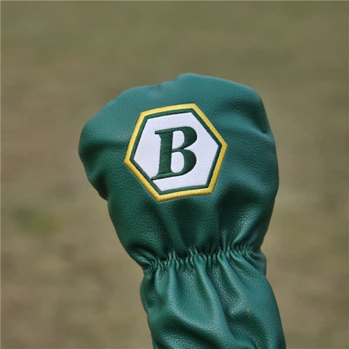 A green golf club head cover with a hexagonal logo featuring a white letter 'B'.