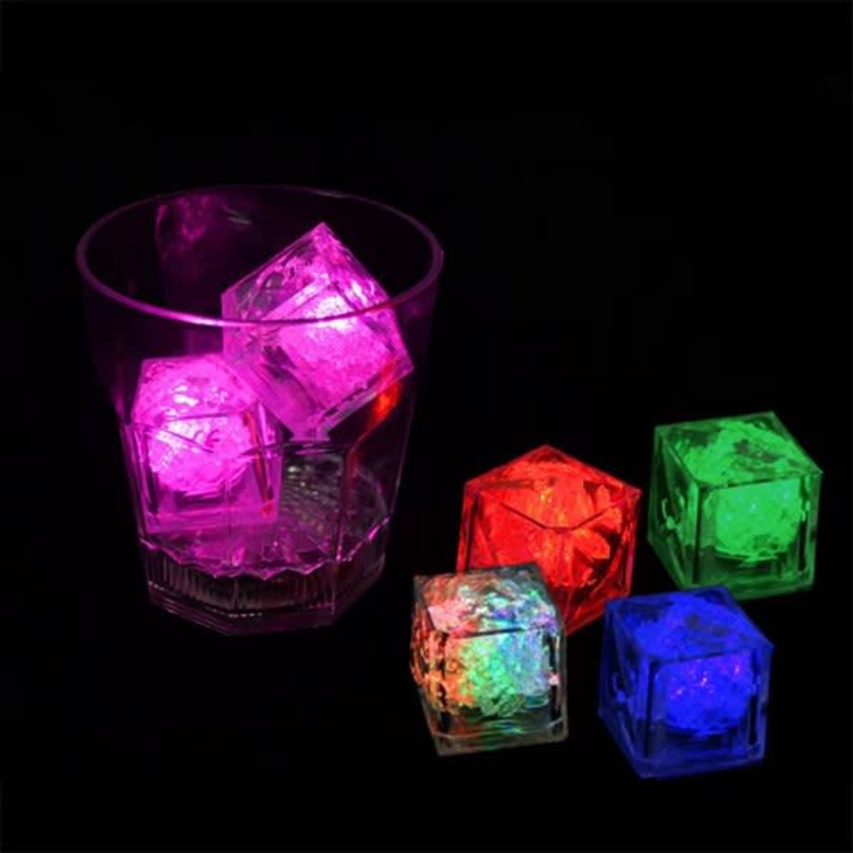 A drink glass contains glowing ice cubes in pink, red, green, and blue against a black background.