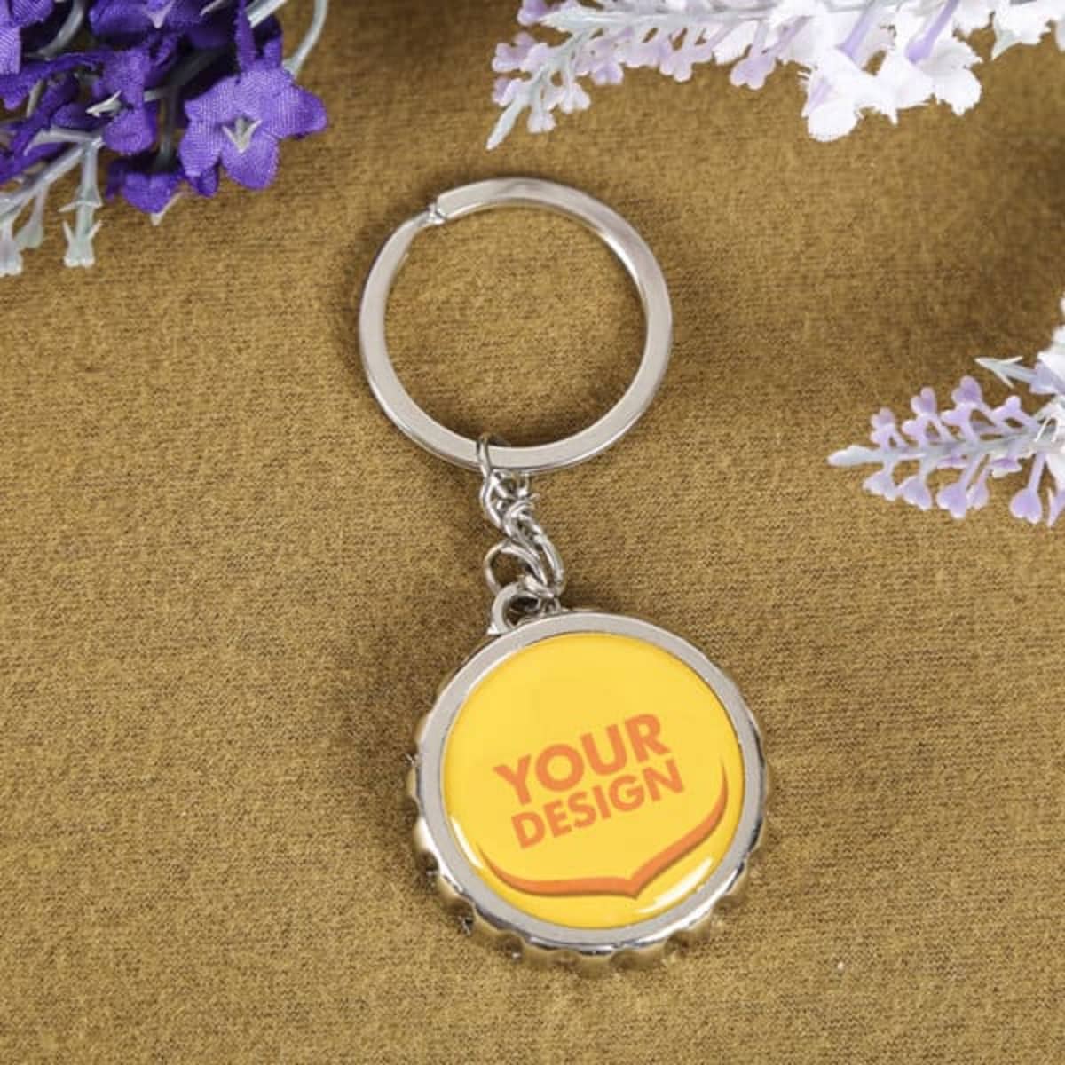 A drink bottle keychain in silver featuring a yellow bottle cap design. Includes a bottle opener and a logo.