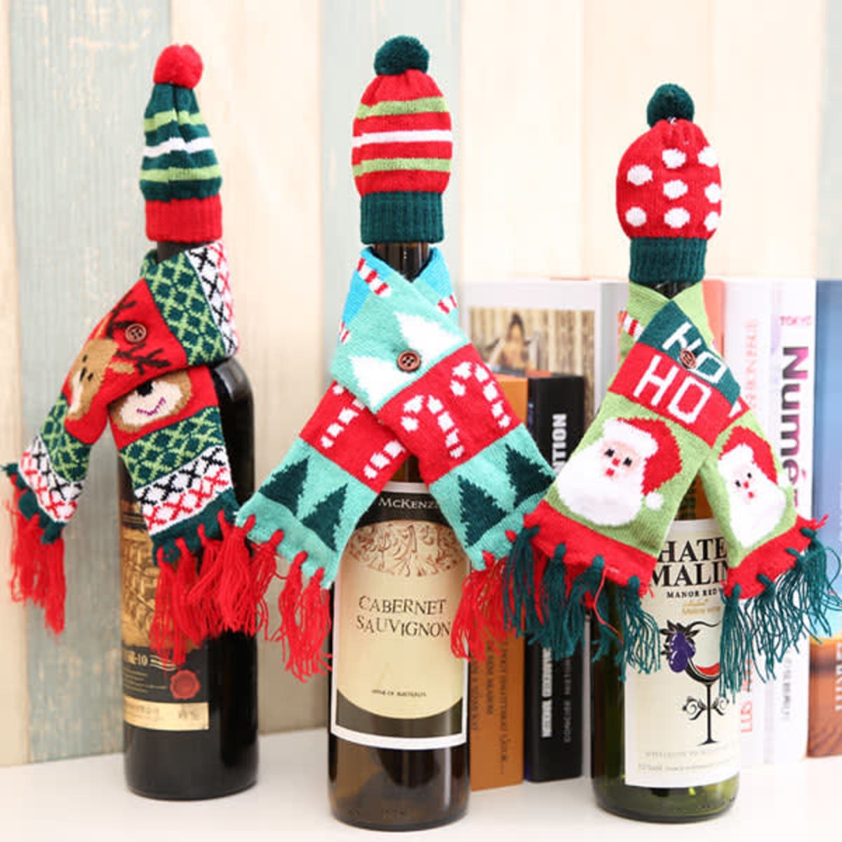 A drink bottle dressed in a red and green knitted hat and scarf, featuring festive patterns and colours.