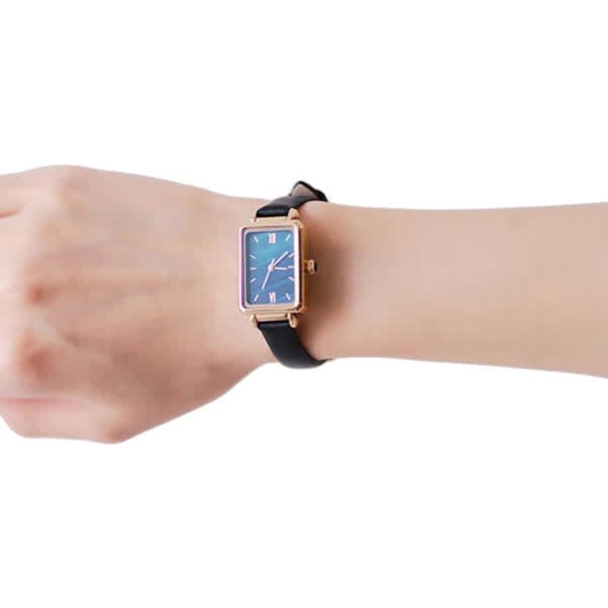 An elegant rectangular quartz watch with a blue face and a black strap worn on a wrist.