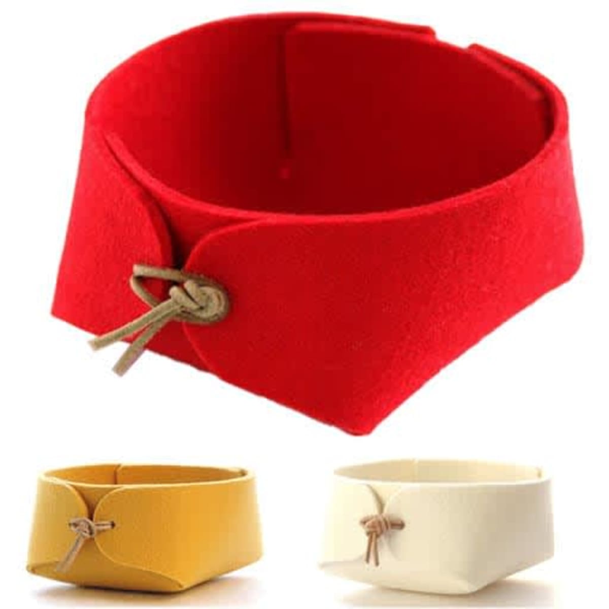 A red felt desktop organiser with two smaller containers in yellow and white, featuring a leather tie detail.