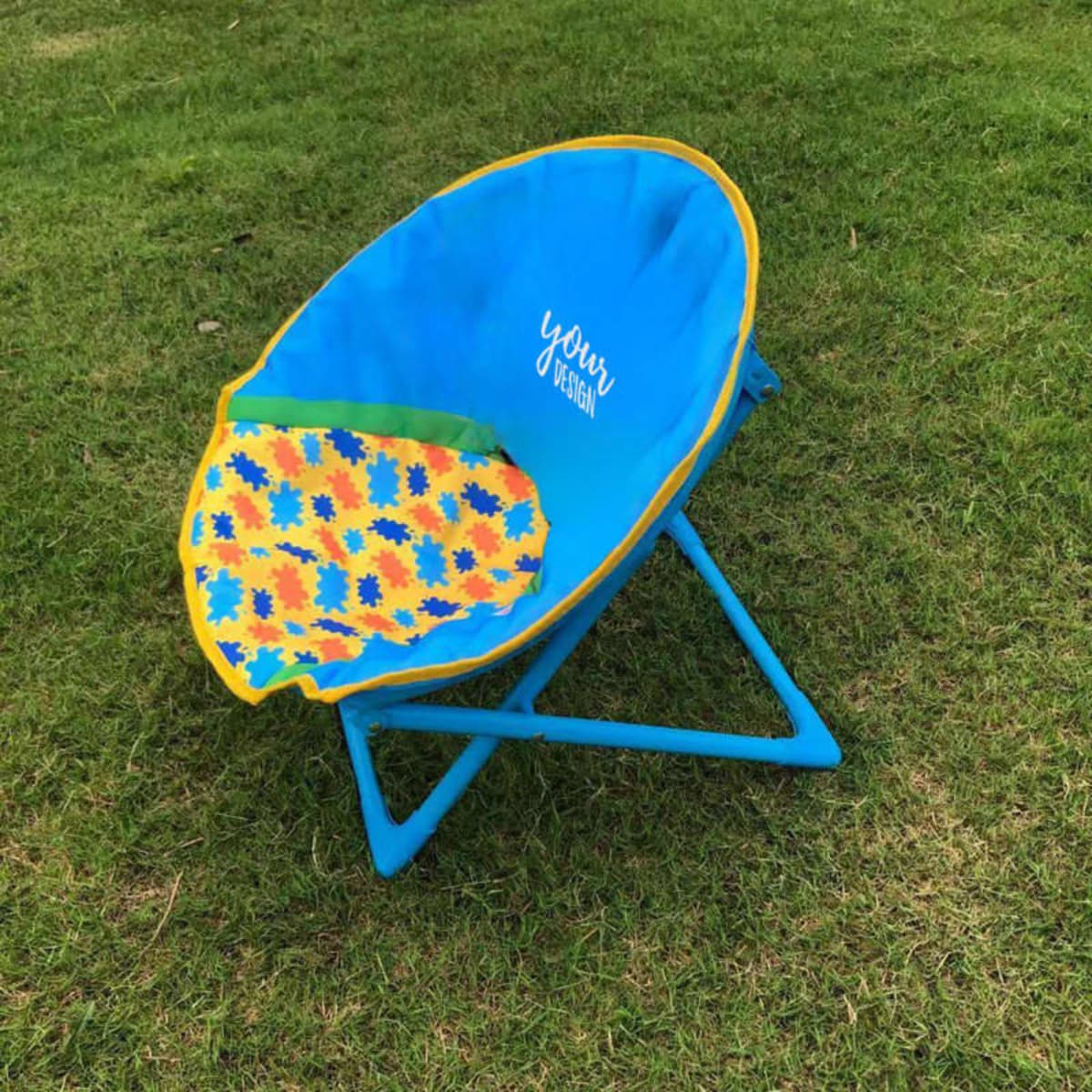 A folding beach moon chair featuring a blue and yellow design with a colourful patterned seat on a grassy surface.
