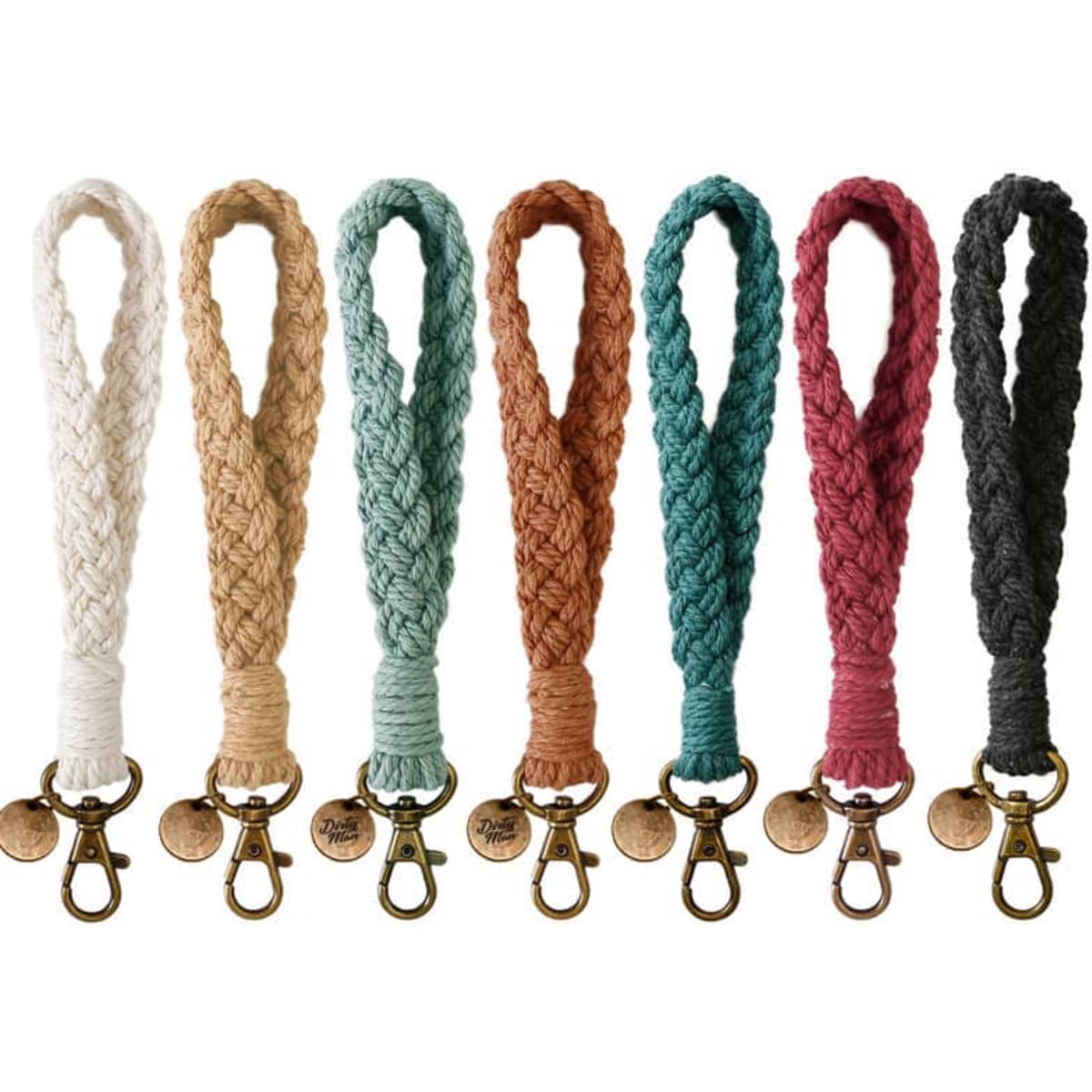 A collection of eight braided macrame phone wrist straps in white, beige, terracotta, green, burgundy, and black. Each has a metal clip.