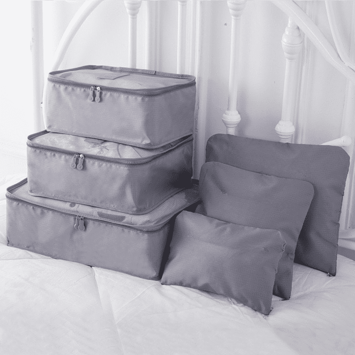 A set of six grey travel storage bags in various sizes, featuring zip closures and a simple design.
