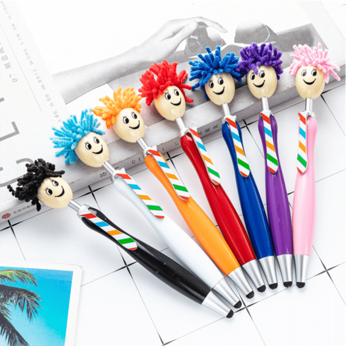 A set of colourful ballpoint pens with mop head styluses, featuring various hair colours and smiling faces.