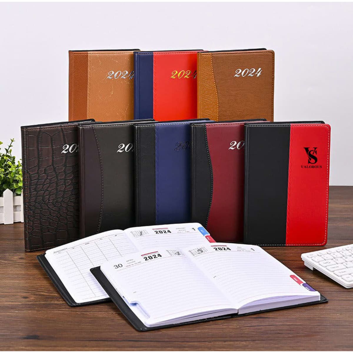 A range of PU leather diaries in various colours, including brown, red, black, and blue, displayed on a wooden table.