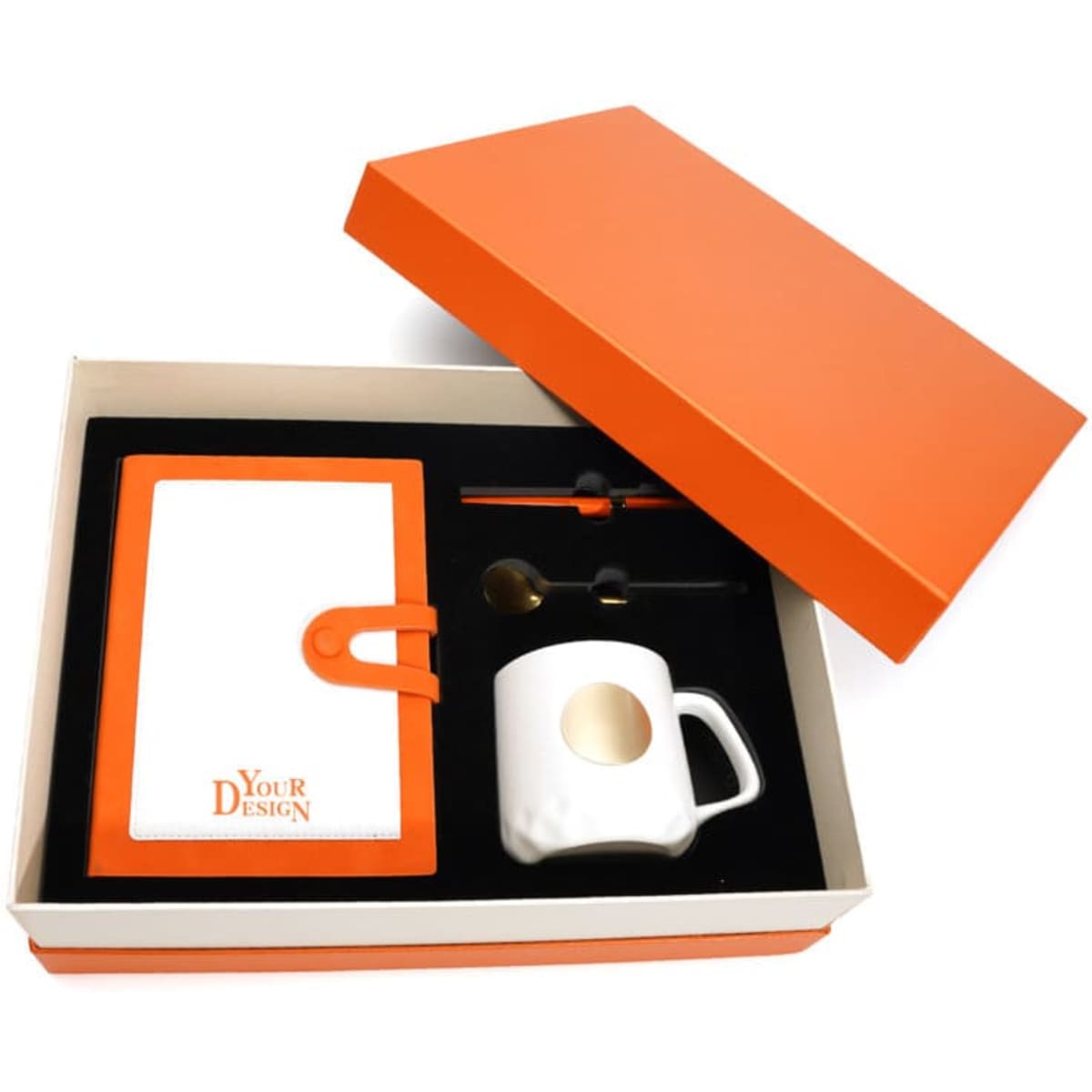 A notebook with an orange cover, a ceramic cup with a gold spot, a pen, and a spoon in an orange box.