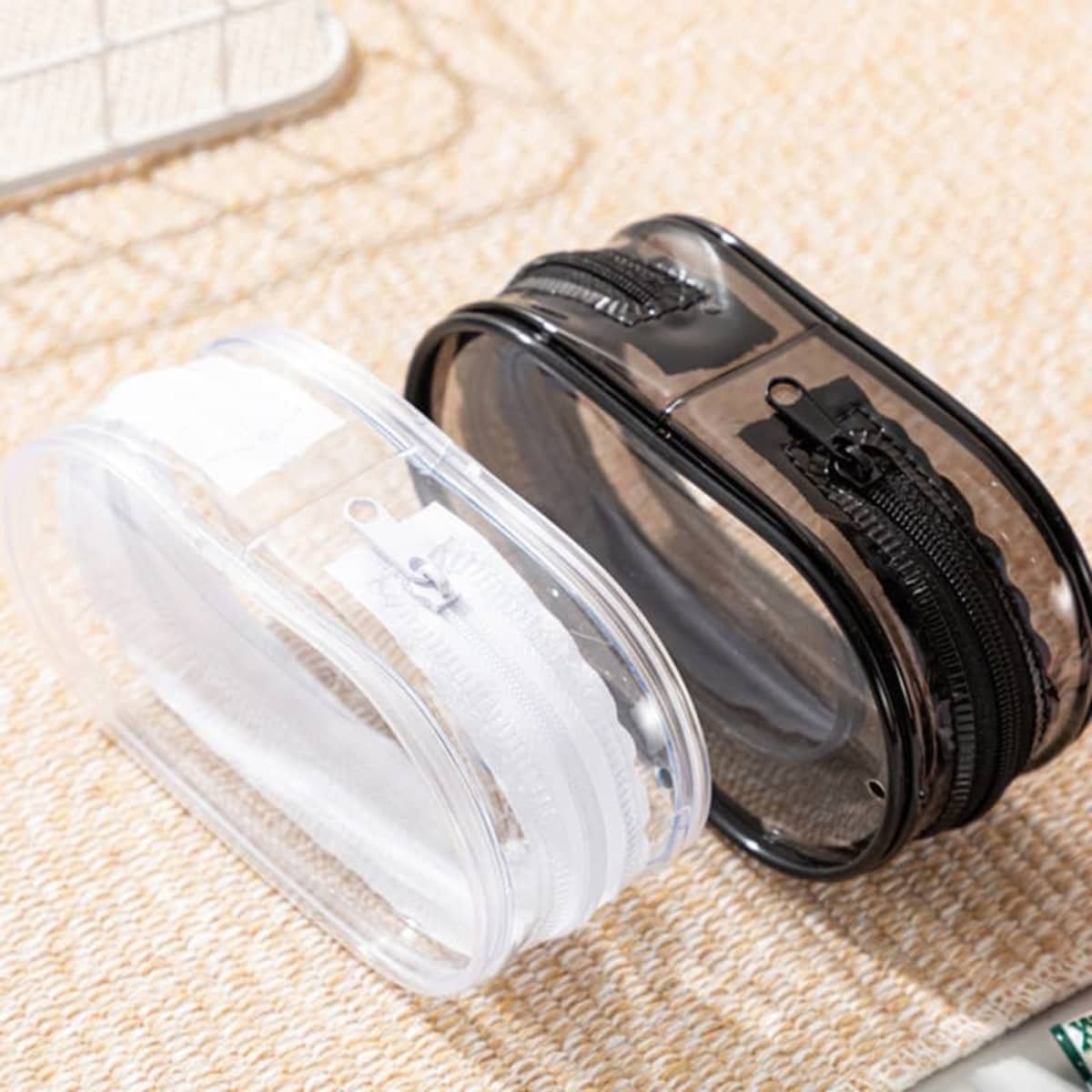A transparent storage bag in clear and black with zippers, designed to hold various small items.