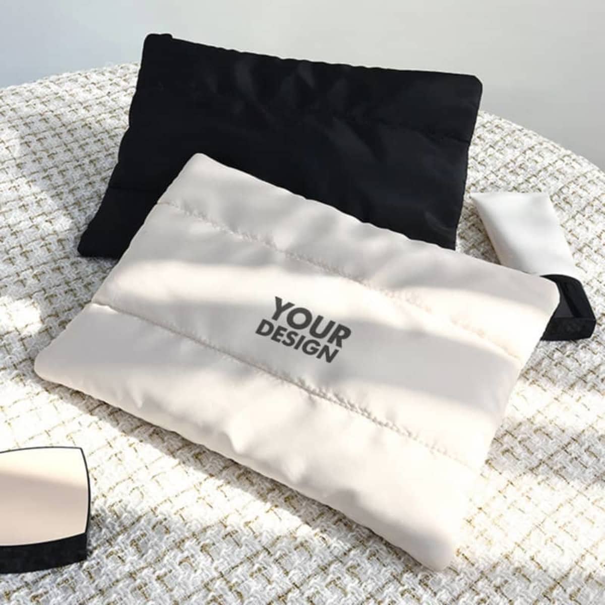 A cotton filled cosmetic bag in cream and black, featuring a logo, placed on a textured surface.