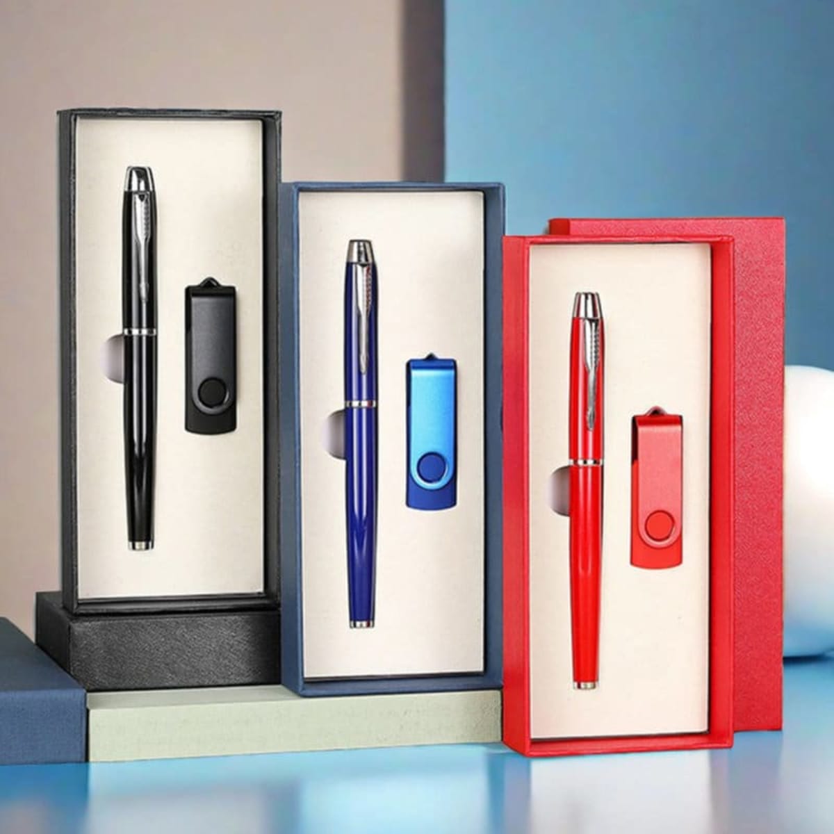 A set of ballpoint pens and USB flash drives in black, blue, and red, presented in stylish boxes.