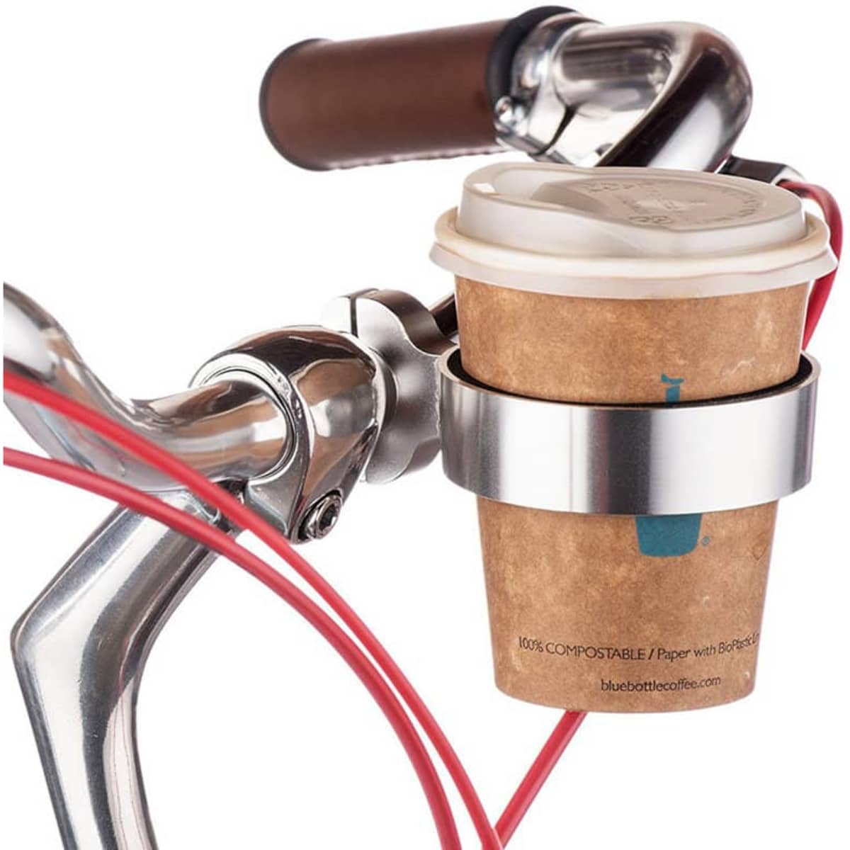 A drink bottle holder in silver, attached to a bike handlebar, holding a coffee cup wrapped in a cardboard sleeve.
