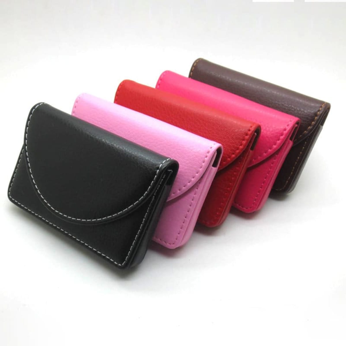A set of four business card holder cases in black, pink, red, and brown, with a simple design and stitched detailing.