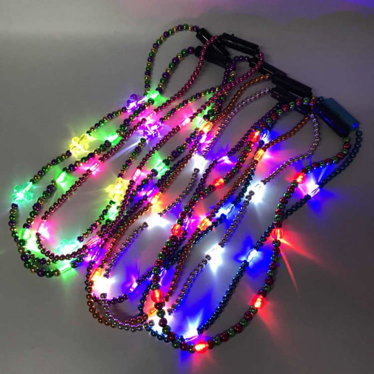 A collection of multicoloured LED bead necklaces illuminated with vibrant lights on a grey background.