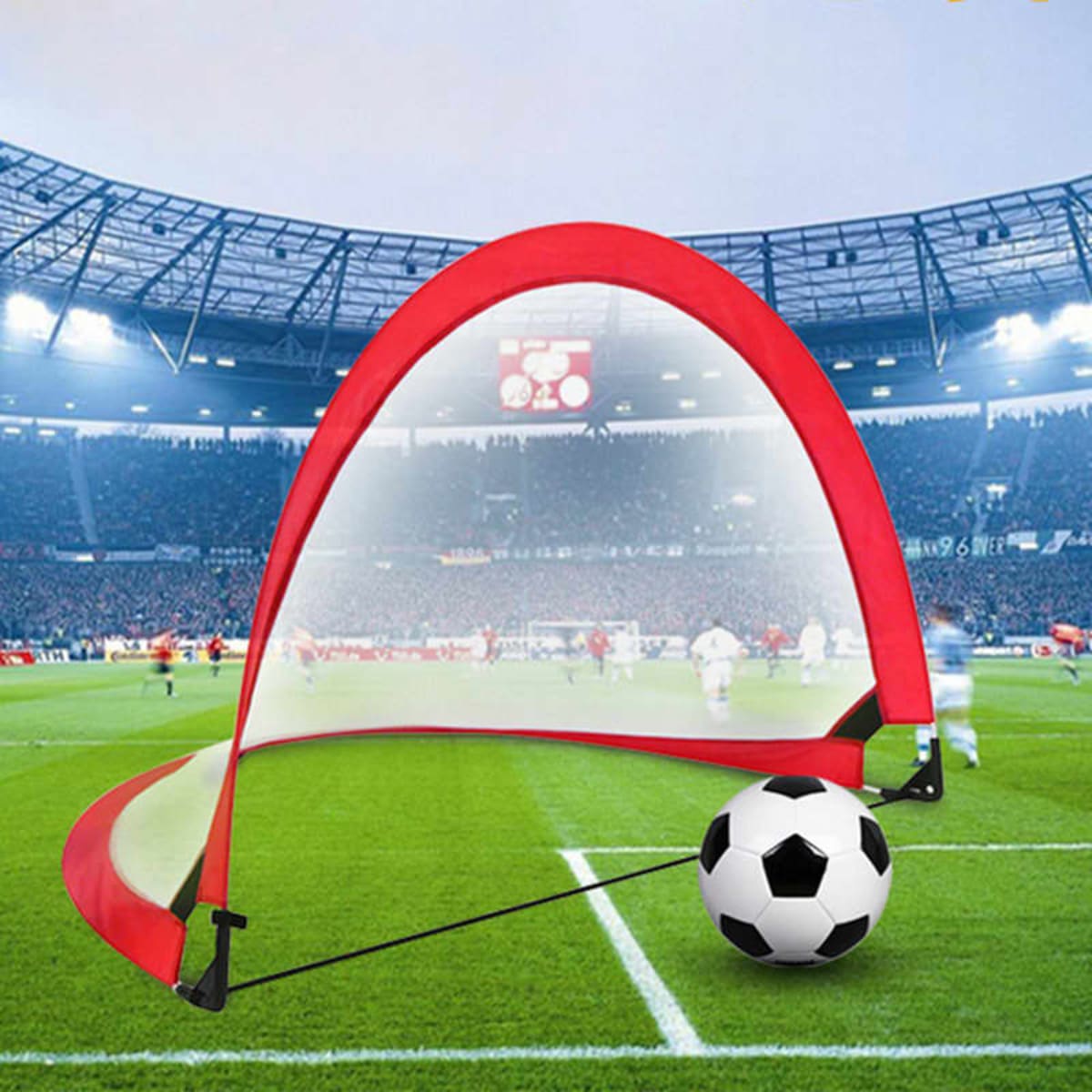 A red pop-up football goal set up on a grassy field, with a black and white soccer ball nearby.