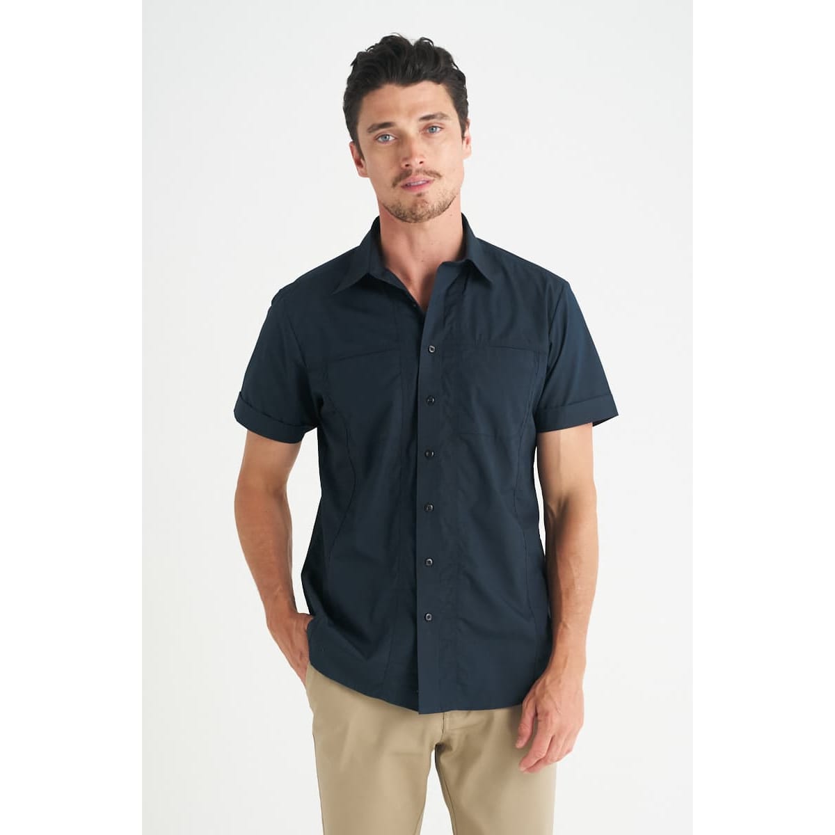 A navy short sleeve button-up shirt for men, featuring a collar and fitted style. The model stands casually with hands in pockets.