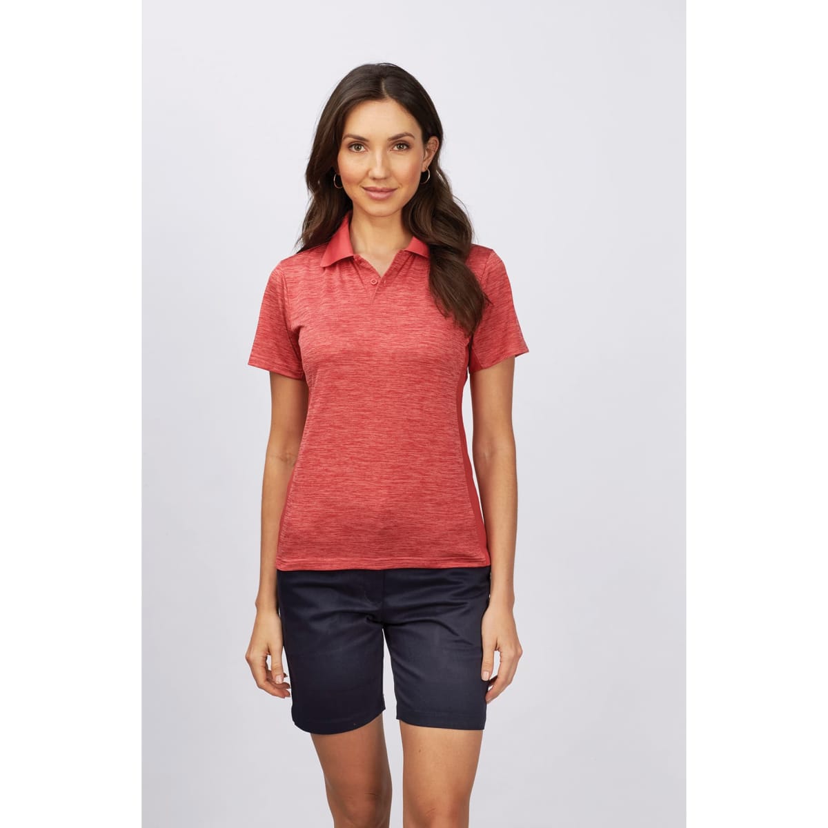 A woman models a red polo shirt paired with navy chino shorts. The outfit features a logo on the shirt.