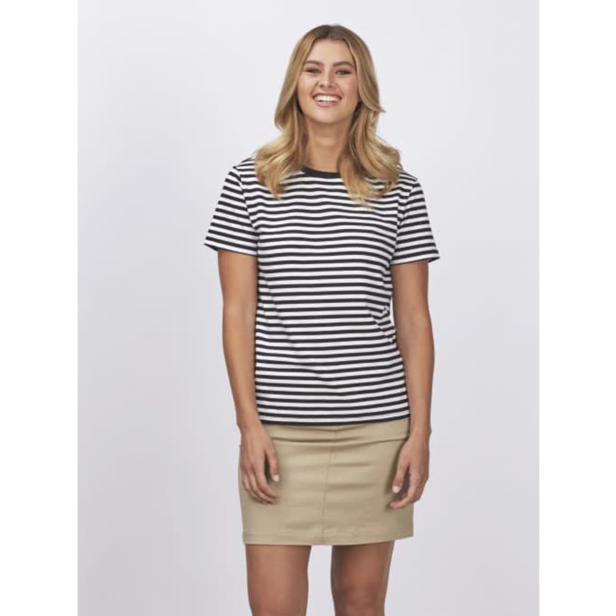 A striped ladies’ t-shirt in black and white, paired with a beige skirt. The model is smiling.