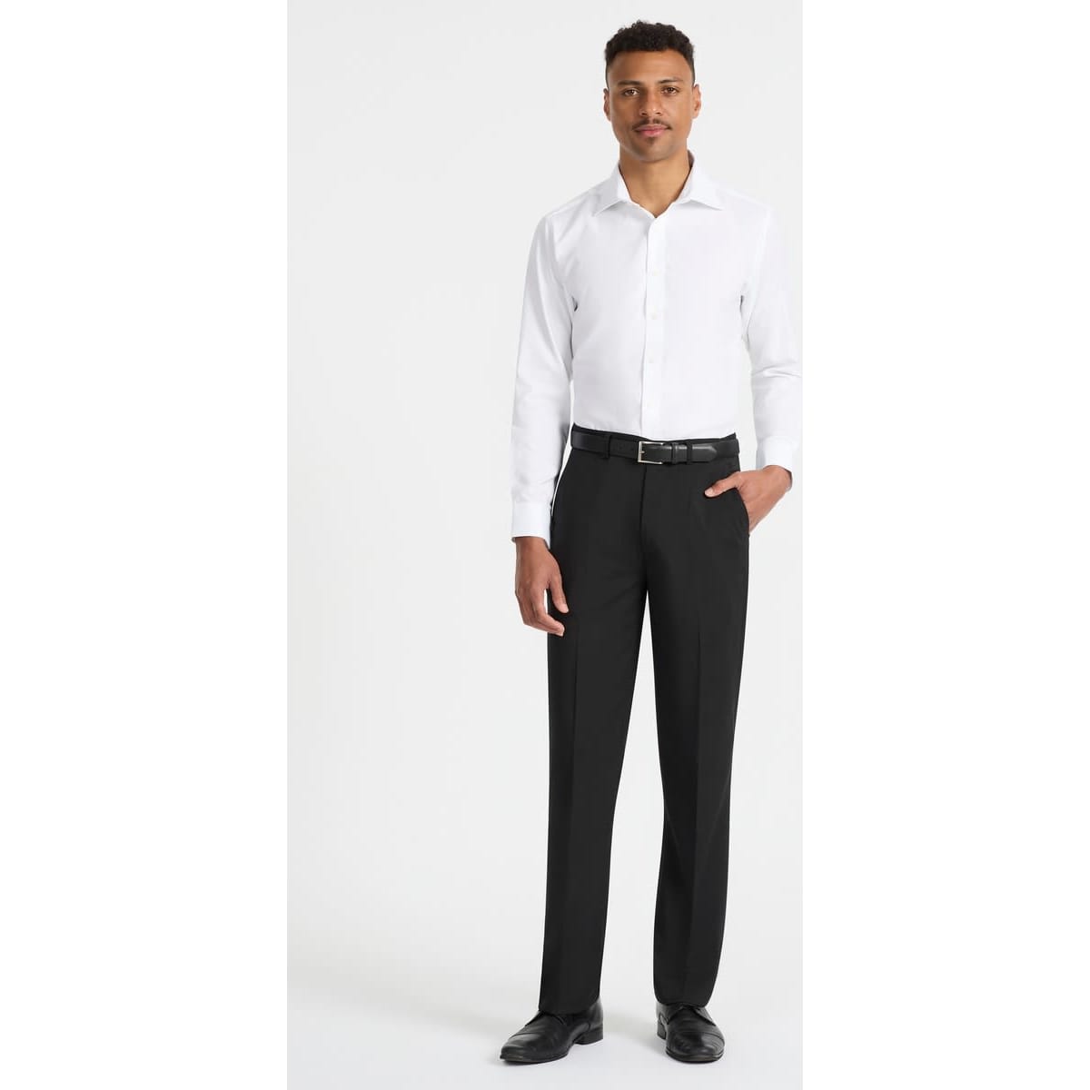 A man wearing a white long sleeve button-up shirt paired with black trousers and shoes, showcasing a sleek look.