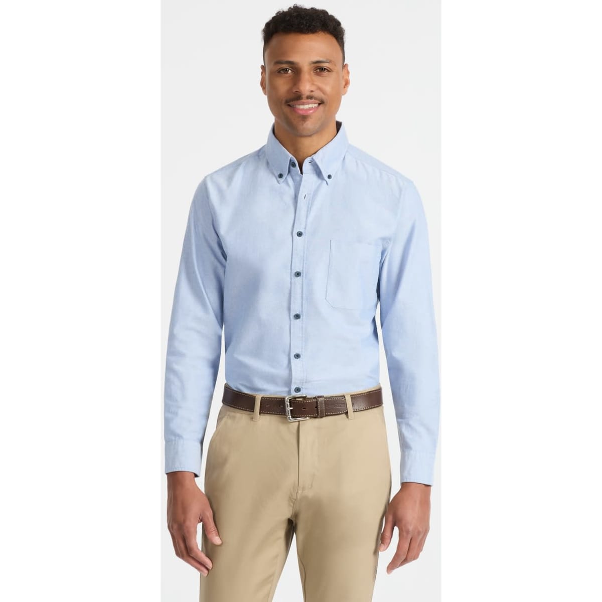A light blue men's long sleeve button-up shirt with a pocket and a logo on the chest, paired with beige trousers.
