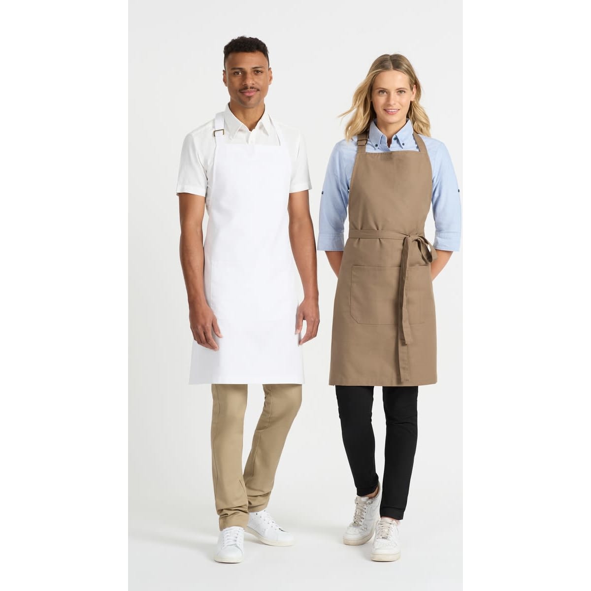 A white apron worn by a man and a khaki apron worn by a woman, both paired with casual shirts and pants.