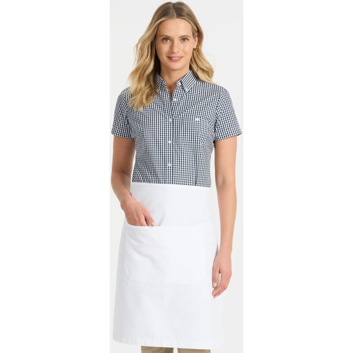 A short sleeve button-up shirt in black and white gingham pattern, paired with a white apron. The model is smiling.